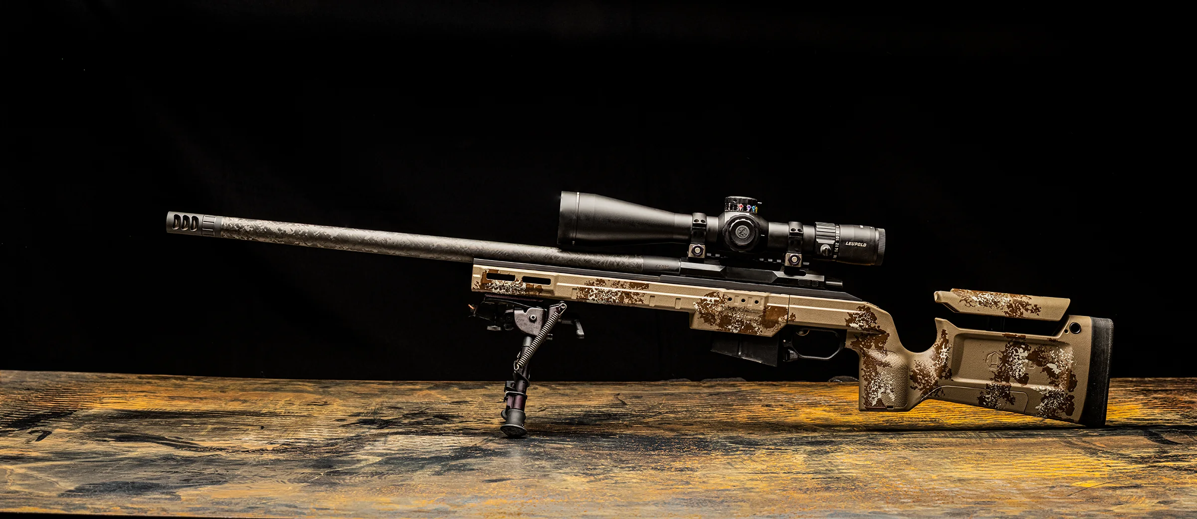 Watchtower Defense Stratis Bravo bolt-action rifle in Westrider Camo, hand-painted tan, brown and white pattern, with scope and bipod