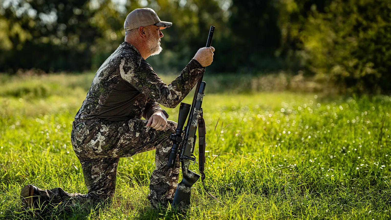 Shooter kneeling in the grass with the Watchtower Defense Stratis bolt-action rifle